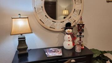 A desk with a lamp, a snowman decoration, a welcome sign, and a small house model.