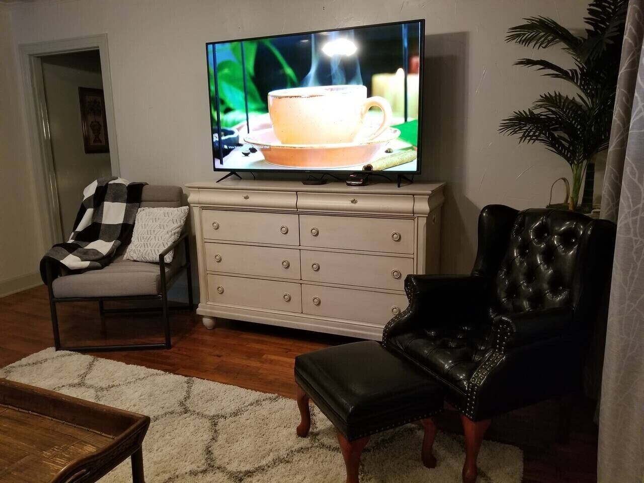 A living room with a television, a sofa, a chair, a coffee table, and a cabinet.