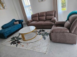 A living room with a brown sofa, a blue sofa, and a round coffee table with a gold frame. - Modern 2BR with Pool Near Beach & City Mall, Nyali (Mombasa)