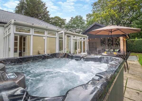 A hot tub with a glass enclosure, a patio area with outdoor furniture, and a covered seating area. - Superb manor house with countryside views. (Bala,)