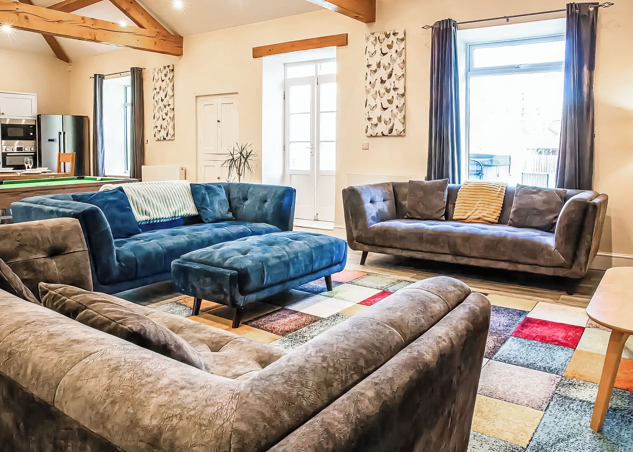 A living room with a pool table, two sofas, and a dining table.
