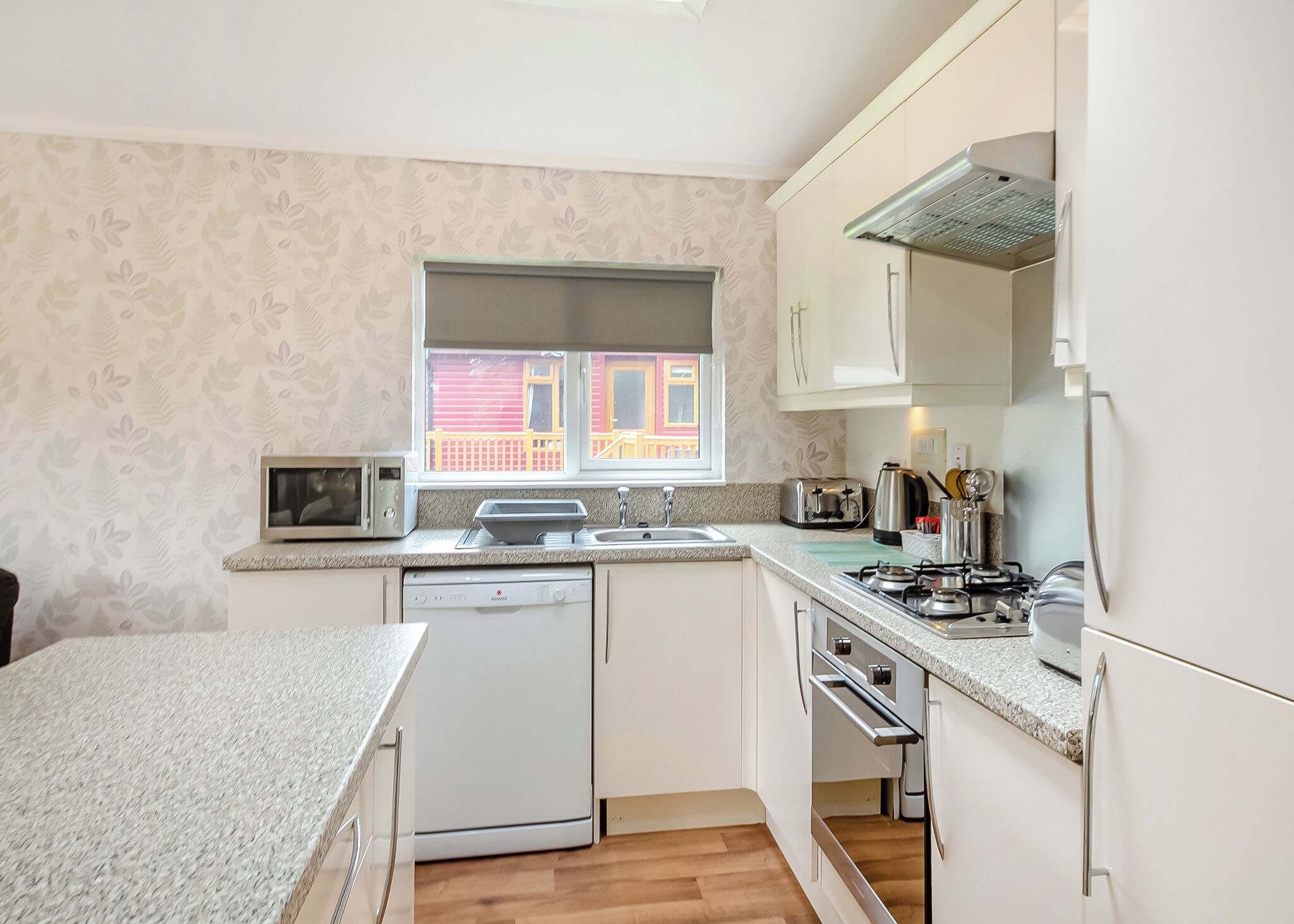 A compact kitchen with a dishwasher, microwave, toaster, and stove.