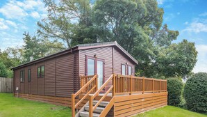 Een gelijkvloers houten vakantiehuisje met een veranda en een trap naar de ingang.