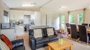 Een moderne keuken met witte kasten, een zwarte leren bank en een eethoek met een houten tafel en stoelen.
