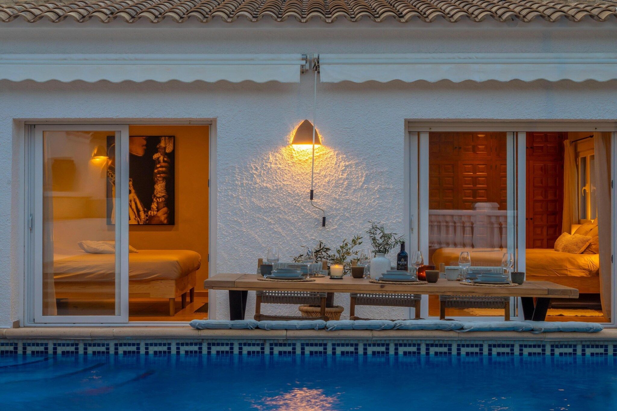 Ein Hotelzimmer mit Pool, einem Essbereich mit Tisch für zwei Personen und einem großen Fenster mit einem Gemälde.
