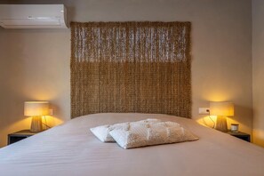 A hotel room with a bed, two bedside lamps, and a wall-mounted air conditioner. - Beautiful villa with pool and stunning view (Alicantie)
