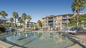 A swimming pool with lounge chairs and palm trees, surrounded by multi-story buildings. - Gorgeous 2-Bed Unit near Riverside Parks (Chiswick)