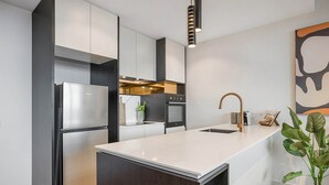 A modern kitchen with a central island, stainless steel appliances, and a minimalist design. - Modern, Executive 1 Bedroom Apartment With Balcony (Cremorne)