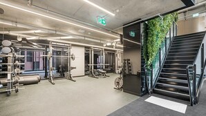 A gym with weightlifting equipment, a staircase, and a green wall. - Modern, Executive 1 Bedroom Apartment With Balcony (Cremorne)