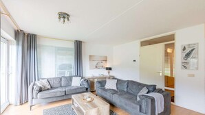 Un salon moderne avec deux canapés gris, une table basse en bois et un tapis à motifs.