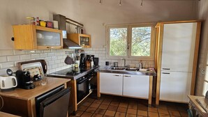 Een kleine keuken met een vaatwasser, kookplaat, spoelbak en een raam dat voor natuurlijk licht zorgt.