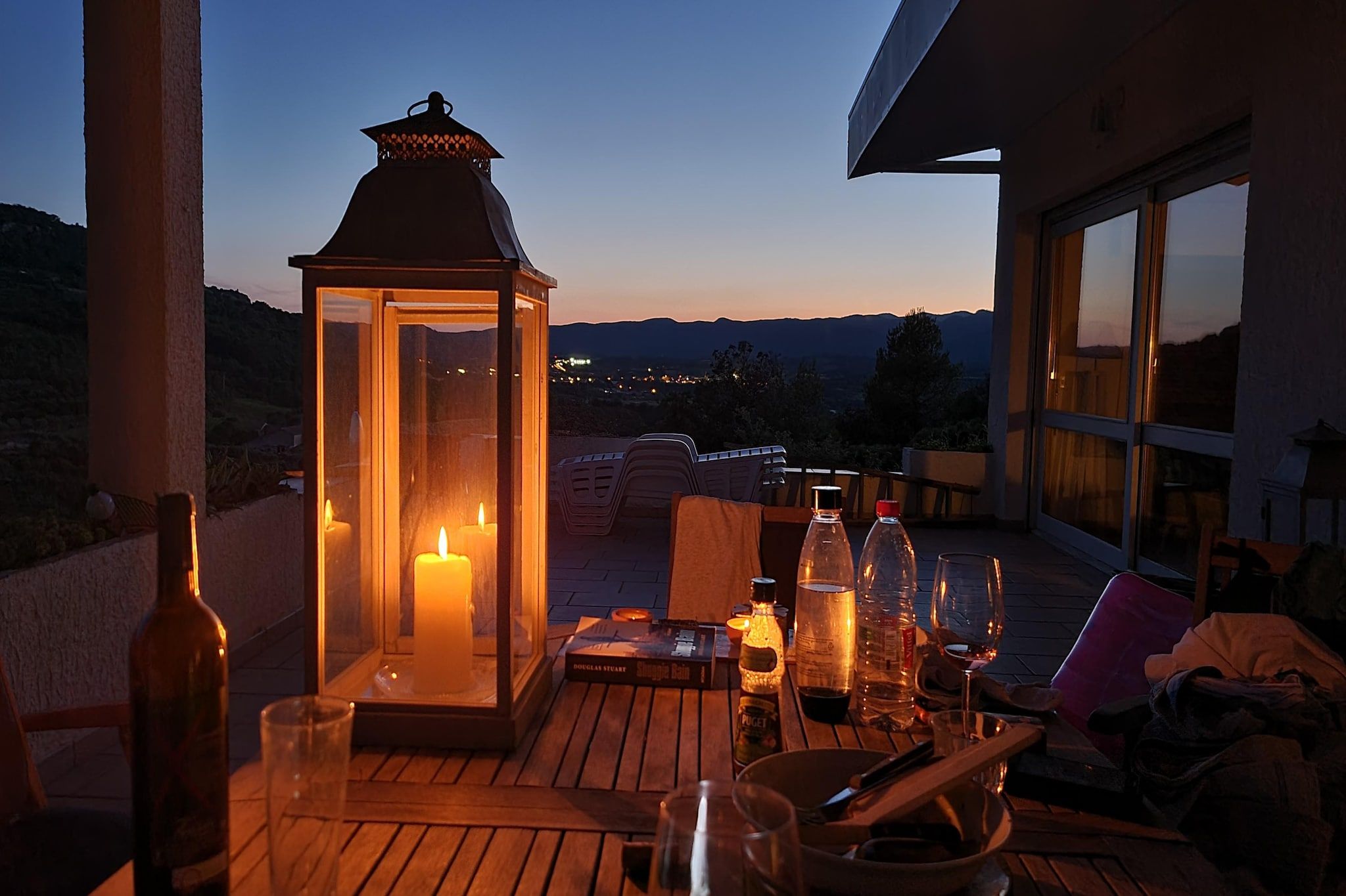 Une terrasse avec une table dressée pour le repas, une lanterne et une vue sur le paysage.