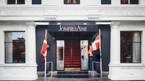 L’entrée de l’hôtel Jomfruane se distingue par un grand escalier, deux drapeaux et une vue dégagée sur l’intérieur grâce aux portes vitrées.