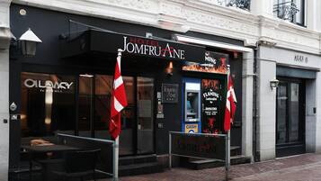 Hotel Jomfruane con fachada negra, entrada visible y un cartel anunciando 'The Mining Lounge'.