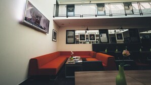 A modern interior with a red sofa, a coffee table, and a dining table with a vase.