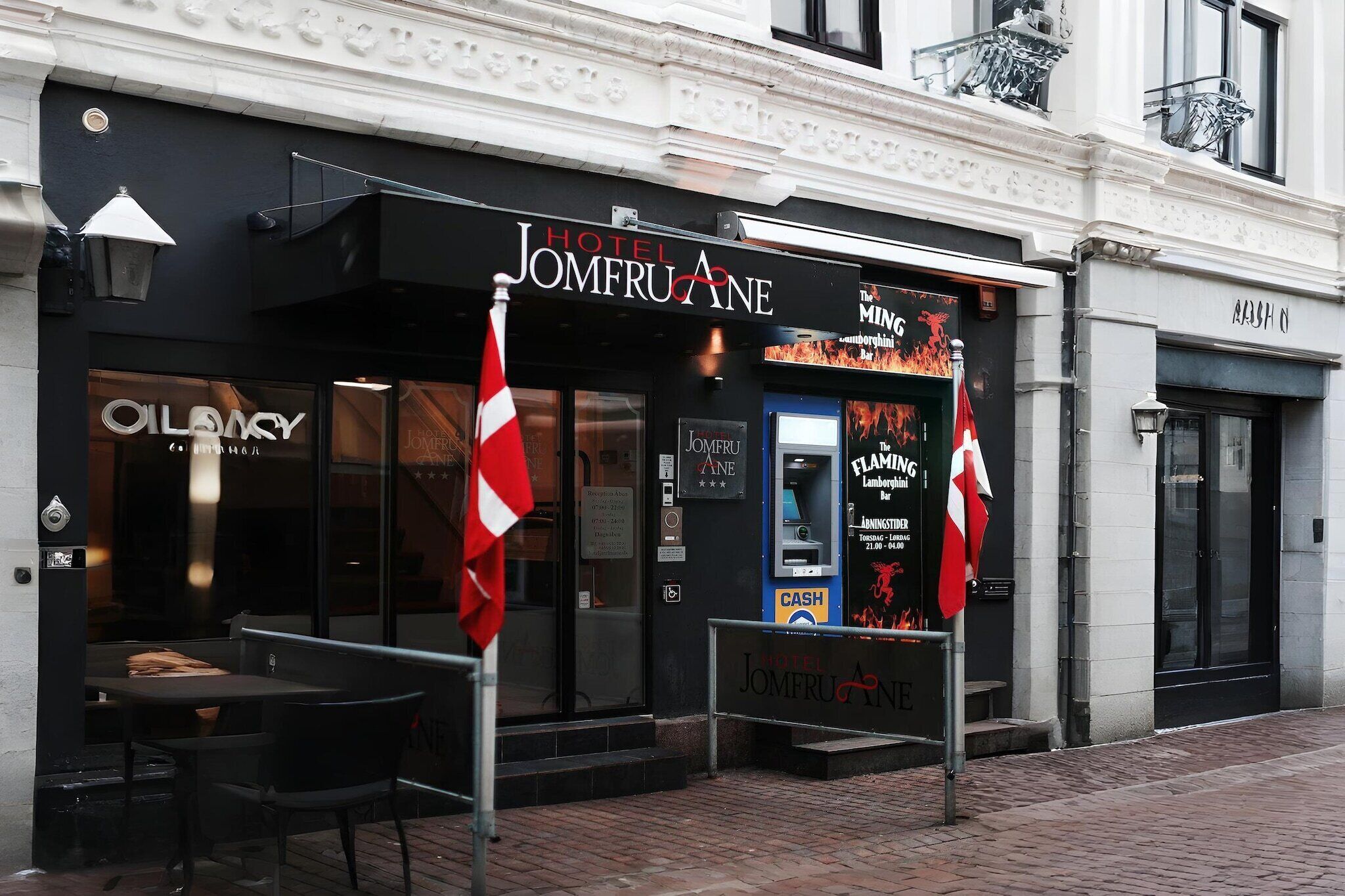 Hotel Jomfruane with a black facade, a visible entrance, and a signboard advertising 'The Mining Lounge'.