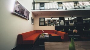 Un intérieur moderne avec un canapé rouge, une table basse et une table à manger. Il y a un balcon avec une balustrade et une vue sur le ciel.