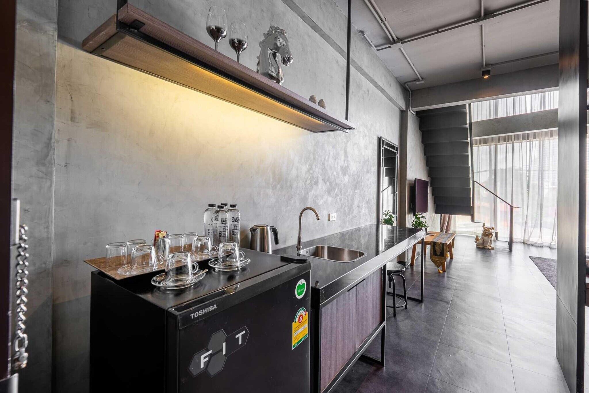 A modern kitchen with a built-in refrigerator, a sink, and a countertop with glasses and bottles.