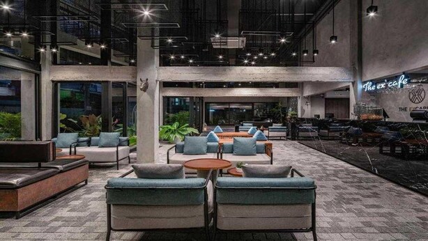 Un espacio interior moderno con varias zonas de estar, incluyendo sofás y sillones, dispuestos alrededor de una mesa de centro.