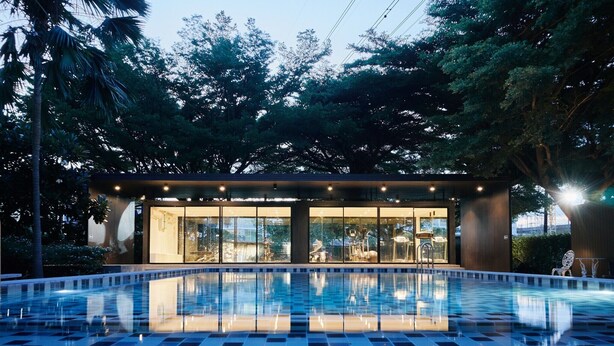 A swimming pool with a checkered pattern, surrounded by trees and a building with large windows. - Platinum Luxury Suite | Modern City Getaway (Bangkok)