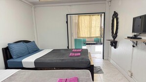 Habitación de hotel con dos camas, televisión y baño visible a través de una puerta abierta.