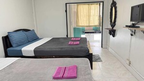 Ein Schlafzimmer mit zwei Betten, einem Fernseher und einem durchgegangenen Tür angedeuteten Badezimmer.