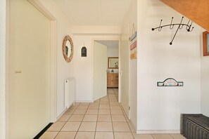 Ein Flur mit Heizkörper, Tür und Spiegel an der Wand.
