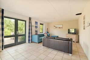 Ett vardagsrum med en soffa, en tv och en matplats med ett bord och stolar.