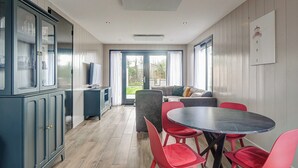 Een moderne keuken met een eetgedeelte, met een groot raam, een ingebouwde televisie en een eettafel met rode stoelen.