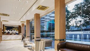A modern lobby with a marble floor, leather seating, and large windows overlooking a fountain. - Superior Twin Retreat | Relaxed Stay for Two (Bangkok)