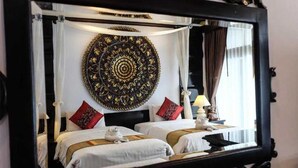 Hotellihuone, jossa on kaksi sänkyä, suuri koristeellinen peili ja koristeellinen seinävaate.