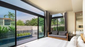 Una habitación de hotel moderna con una cama grande, una zona de estar con vistas a una piscina y un balcón con vistas al entorno verde.