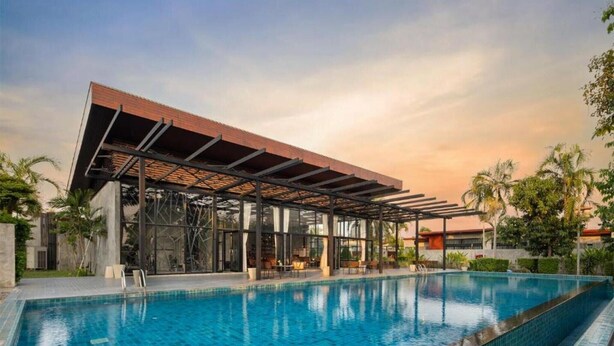Un área de piscina moderna con una zona de estar cubierta y una piscina azul cristalina.