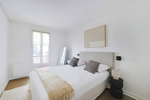 Una camera da letto con un letto grande, un comodino, uno specchio e una finestra.
