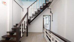 A staircase with wooden steps and white railings, leading to a room with a light-colored floor and a view of the sky through a window. - La Or Heritage Suites MRT Hua Lamphong (Bangkok)