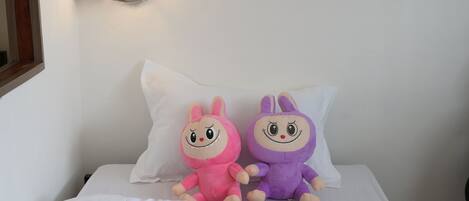 A bed with white bedding and two plush toys on it.