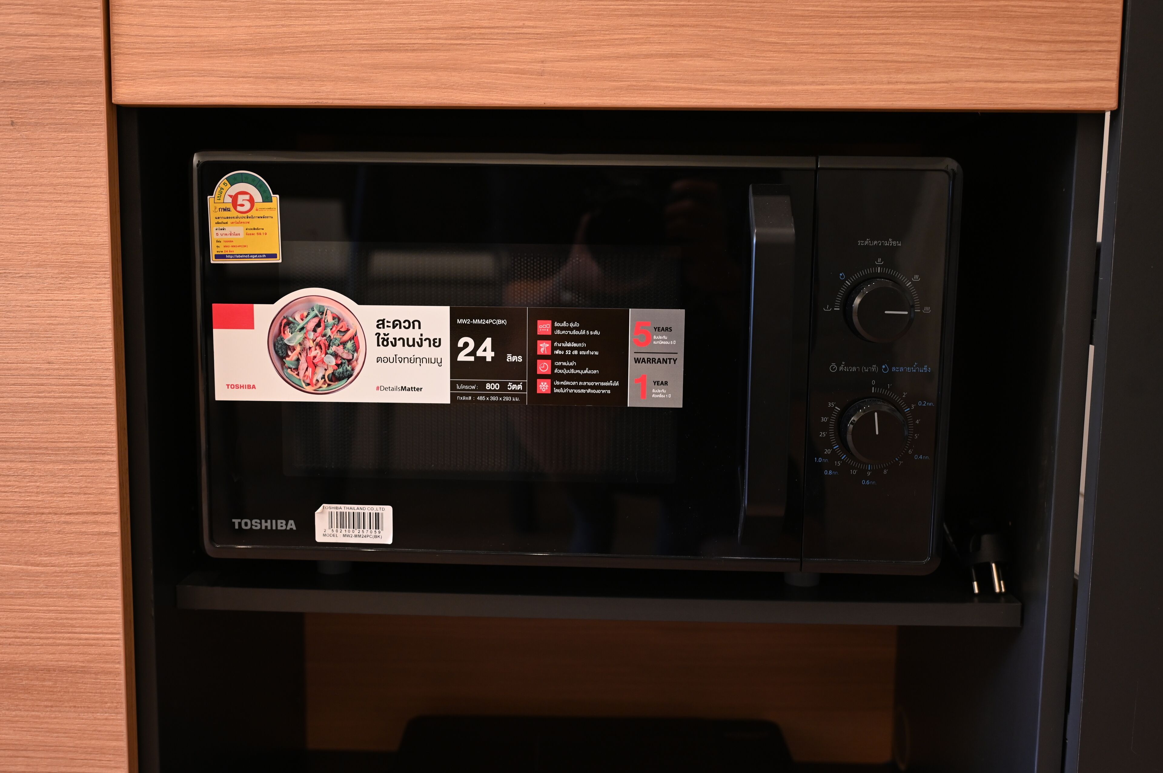 A microwave with a Toshiba label, a 24-hour timer, and a 5-year warranty sticker.