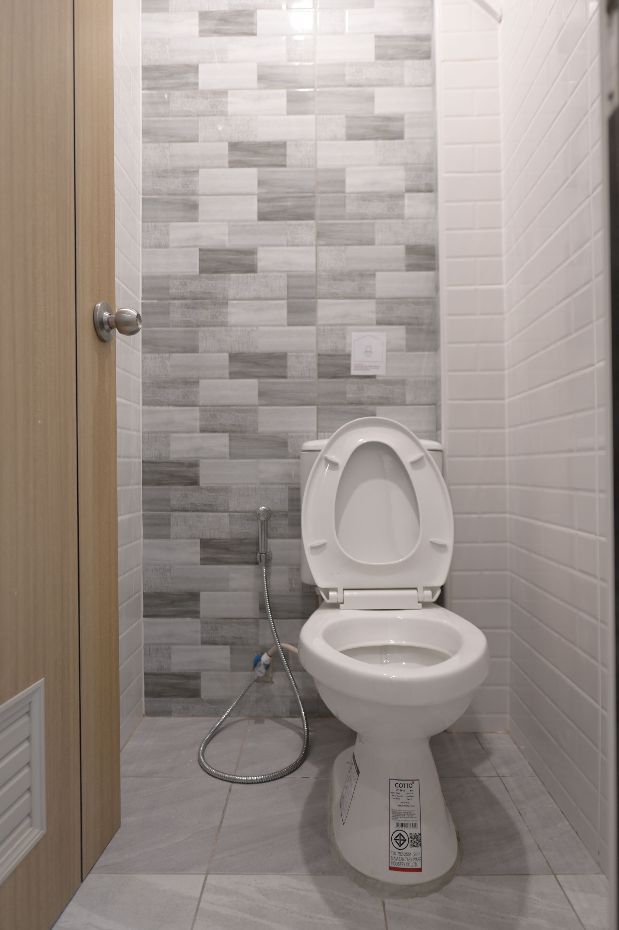 A small bathroom with a toilet, a shower, and a toilet paper holder.