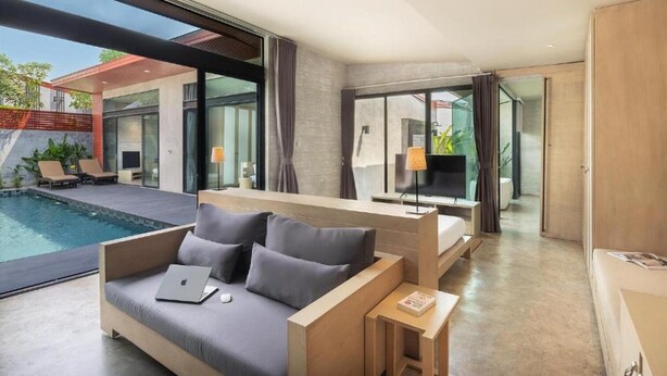 A modern hotel room with a large bed, a desk, and a view of the pool area. - Spacious 3-Bedroom Family Pool Villa (Pattaya)