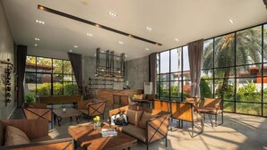 A spacious lounge area with modern furniture, large windows offering views of greenery, and a stylish ceiling design. - Spacious 3-Bedroom Family Pool Villa (Pattaya)