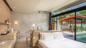 A modern hotel room with a large bed, a desk, and a view of a swimming pool. - Spacious 3-Bedroom Family Pool Villa (Pattaya)