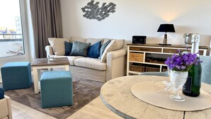 Ein modernes Wohnzimmer mit rundem Tisch, einer Couch, einem Couchtisch und einer Wanddekoration.