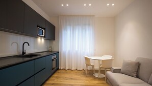 A modern kitchen with dark cabinets, a microwave, and a sink. There is a dining area with a white table and chairs. - Luxury Freedom Minerva (Palermo)