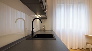 A modern kitchen with a sleek black countertop, stainless steel sink, and a black faucet. - Luxury Freedom Minerva (Palermo)