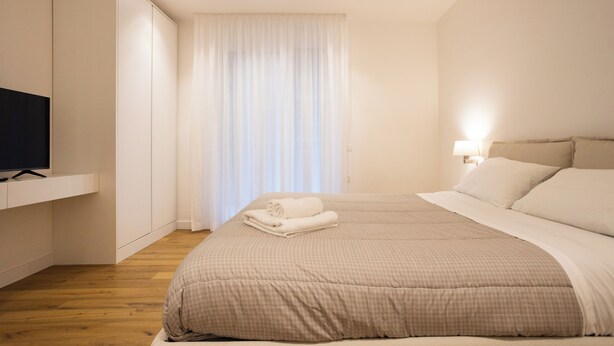 A bedroom with a bed, a TV, and a window with curtains. - Luxury Freedom Minerva (Palermo)