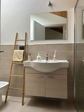 A bathroom with a white sink, mirror, and a bamboo ladder. - New standalone apartment 20 meters from the ocean (Santo Stefano al Mare)