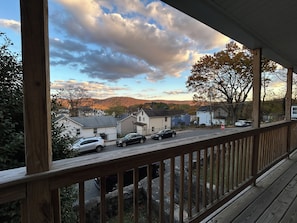 Eine Holzterrasse mit Blick auf eine Wohnstraße, Häuser und einen Berg in der Ferne.
