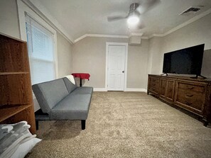 A living room with a grey sofa, a wooden cabinet, a television, and a door. - Walk to West Point USMA - Marvelous 4 Bedroom house in Highland Falls -Sleeps 12 (Highland Falls)