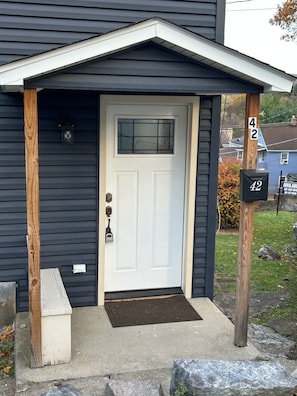 Ein dunkelblaues Haus mit einer weißen Haustür, einem Briefkasten und einer Hausnummer.
