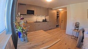 Une cuisine moderne avec des meubles en bois, un four à micro-ondes et un coin repas comprenant une table et des chaises en bois.